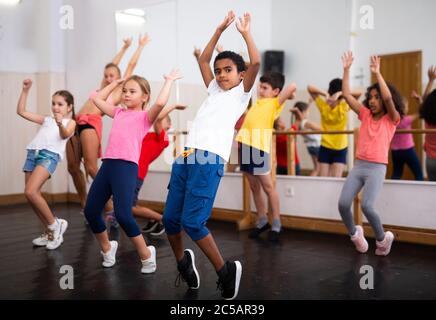 Allegro presetino ragazze e ragazzi hip hop danzatori facendo allenamento di danza con allenatore femminile durante la classe di gruppo Foto Stock