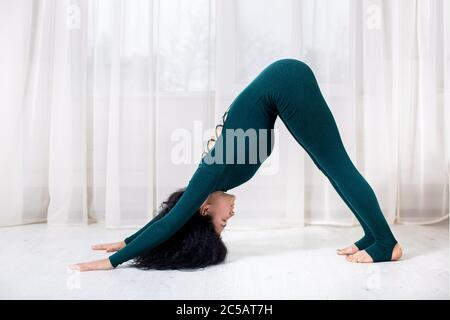 ragazza sola nello sport facendo esercizi di yoga sul pavimento nella stanza della luce durante la quarantena di covid 19 cotonavirus rimanere casa sicuro mondo. Foto Stock