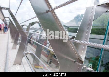 ponte in vetro con cavi in acciaio tensionato e supporti per ringhiera in acciaio. Foto Stock