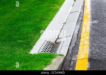 sistema di drenaggio bordo con griglia in calcestruzzo per il drenaggio delle acque piovane nella fogna su un lato della strada dopo la pioggia, non chiudere nessuno. Foto Stock