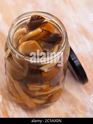 Mescolare i vari funghi sottaceto in un vaso di vetro aperto su un tavolo di legno Foto Stock