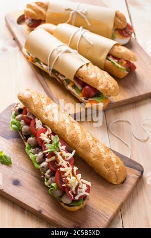 Panini freschi sottomarini con varietà di ripieni su sfondo di legno Foto Stock