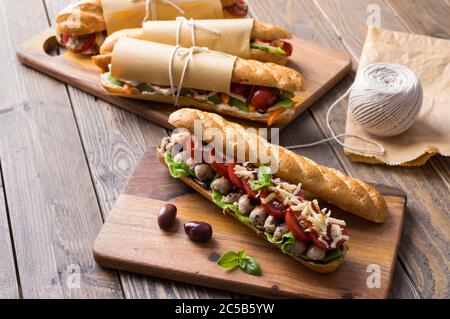 Panini freschi sottomarini con varietà di ripieni su sfondo di legno Foto Stock