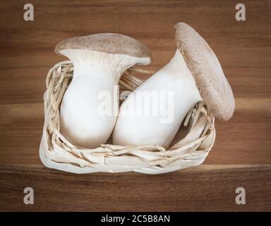 Due funghi in un piccolo cesto su una tavola di legno Foto Stock