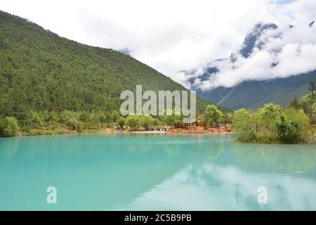 il lago verde riflette la montagna sotto le nuvole bianche Foto Stock