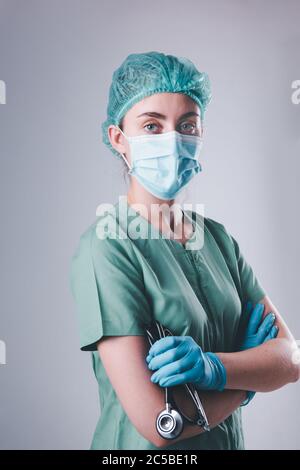 Medico femminile in maschera protettiva e cappuccio medico su sfondo isolato, Closeup ritratto di medico chirurgo medico indossando maschera medica e tenuta Foto Stock