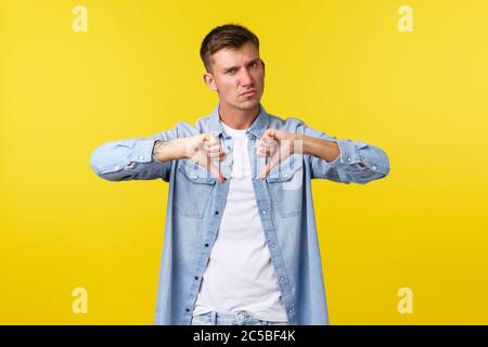 Stile di vita, emozioni della gente e concetto di svago estivo. Sconvolto e insoddisfatto biondo bel ragazzo gracing, scuotendo testa in negazione o disapprovazione Foto Stock