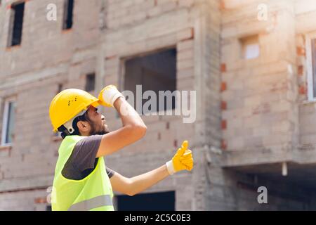 Ingegnere di costruzione mostrando pollici in alto segno al cantiere Foto Stock