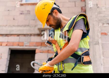 [Costruzione di un cassone di sicurezza] lavoro in altezza. Dispositivo anticaduta per l'operatore con ganci per imbracatura anticaduta su fuoco selettivo. Constru Foto Stock