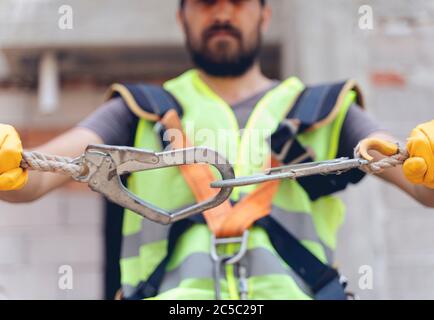 Lavori in altezza. Dispositivo anticaduta per lavoratori con ganci doppi per imbracatura per il corpo di sicurezza su fuoco selettivo. Lavoratore come sfondo. Foto Stock