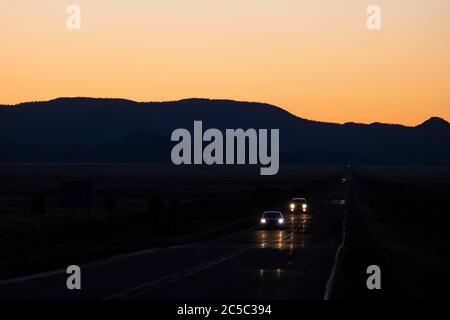 Fari di auto su un solo tratto o strada nel deserto del New Mexico in serata Foto Stock