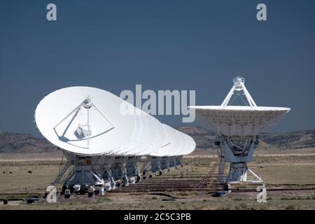Linea di radiotelescopi multipli in fila con una parabola sola rivolta verso l'alto in corrispondenza del VLA (Very Large Array) Foto Stock