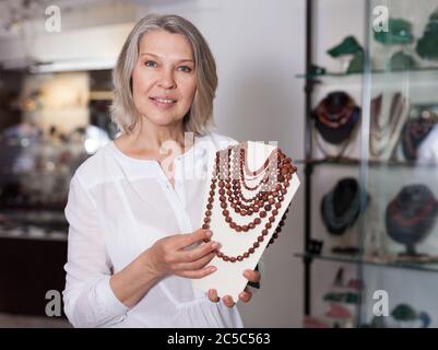 Venditore femmina dimostra di pietra dorata collana Foto Stock
