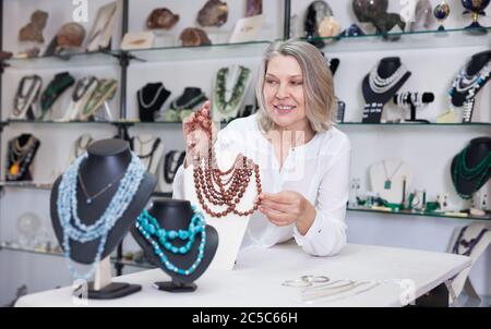 La donna offre di acquistare alla moda di pietra dorata collana in negozio di Gioielleria Foto Stock