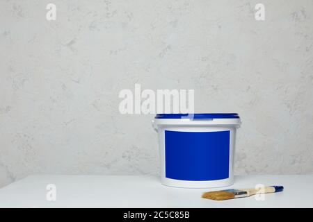 Chiudere la tazzola vuota di vernice blu e spazzolare sul tavolo. Mockup per il design. Spazio per il testo Foto Stock