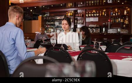 Attraente ragazza con fidanzato pasto scegliendo dal menu nel ristorante accogliente Foto Stock