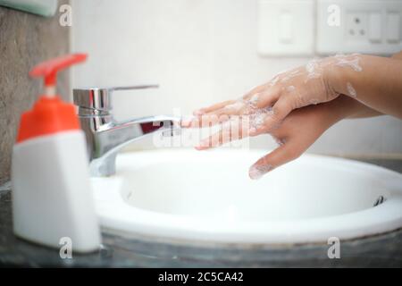 Lavarsi delicatamente le mani con sapone liquido per evitare di contrarre infezioni e retroterie Foto Stock