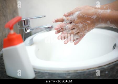 Lavarsi delicatamente le mani con sapone liquido per evitare di contrarre infezioni e retroterie Foto Stock