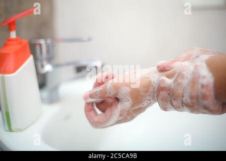 Lavarsi delicatamente le mani con sapone liquido per evitare di contrarre infezioni e retroterie Foto Stock