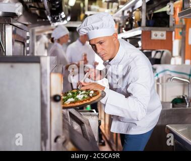 Ritratto di certi chef lavorano nel moderno ristorante cucina, prepara la pizza fuori del forno Foto Stock