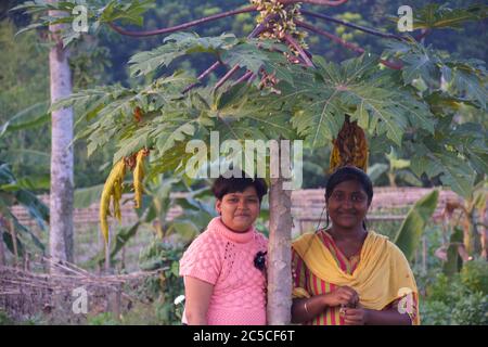 Due belle ragazze indiane sorridenti adolescenti che si trovano sotto una pianta di papiya, focalizzazione selettiva Foto Stock