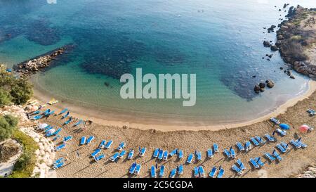 Veduta aerea dall'alto della spiaggia di Sirena a Protaras, Paralimni, Famagosta, Cipro. La famosa attrazione turistica della baia di Sirina con lettini, sabbia dorata, Foto Stock