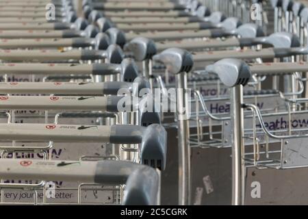 Closeup di carrelli per bagagli accatastati fuori dal Queens Terminal, Heathrow Airport, Londra, Regno Unito Foto Stock