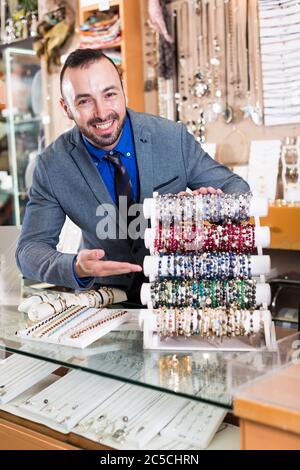 Sorridente venditore che mostrano differenti bracciali in gioielleria Foto Stock