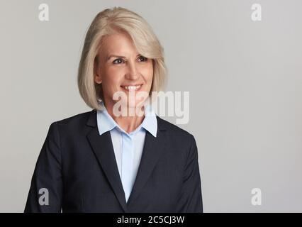 Bella donna matura di affari isolato su sfondo bianco. Vecchia signora sorridente e guardante via. Foto Stock