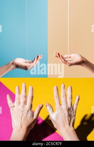 collage di mani femminili in schiuma di sapone, e sotto il sapone liquido che scorre su sfondo multicolore Foto Stock