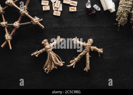 vista dall'alto di bambole voodoo, rune scandinave, pentagrammi, candele e cristalli su nero Foto Stock