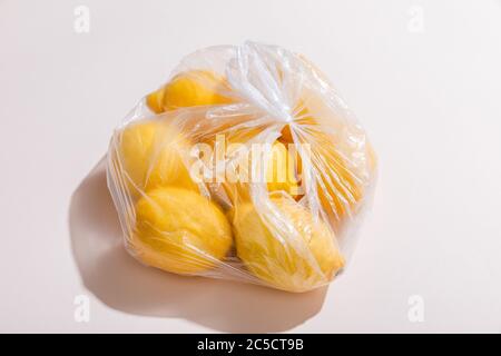 limoni gialli freschi in sacchetto di plastica su tavola grigia Foto Stock