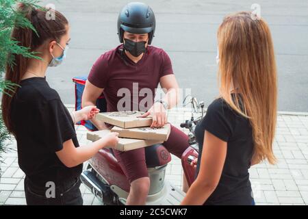 consegna di cibo da parte del corriere in una maschera medica durante la quarantena. Foto Stock