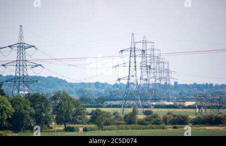 Una fila di piloni di elettricità si dipanano attraverso la campagna nel Regno Unito. Foto Stock