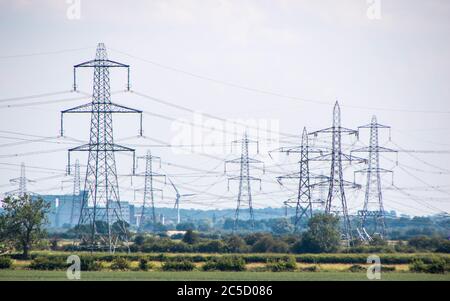 Una fila di piloni di elettricità si dipanano attraverso la campagna nel Regno Unito. Foto Stock