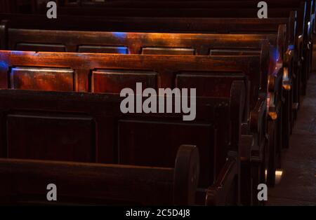 Chiesa pews. La luce solare filtrata attraverso la finestra di vetro colorato. Messa a fuoco selettiva. Foto Stock