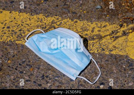 Maschera blu protettivo del coronavirus scartata in strada Foto Stock