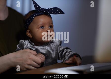 Ragazza africana del bambino seduta al tavolo sulle ginocchia della madre Foto Stock