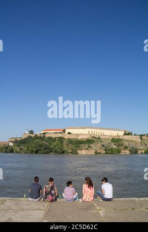 NOVI SAD, SERBIA - 7 GIUGNO 2015: Persone che si siedono insieme di fronte alla Fortezza di Petrovaradin a Novi Sad sul Danubio, in un pomeriggio estivo di sole. IO Foto Stock