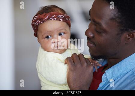 Uomo africano che tiene il bambino sulle sue mani e gioca con lei Foto Stock