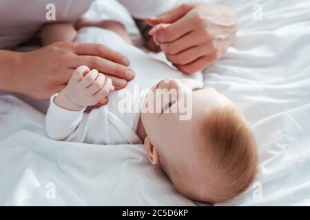 vista ritagliata dell'uomo che tocca adorabile ragazzino in romper Foto Stock