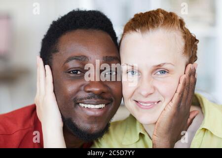 Ritratto di giovane coppia multirazziale amorevole guardando la macchina fotografica e sorridendo Foto Stock