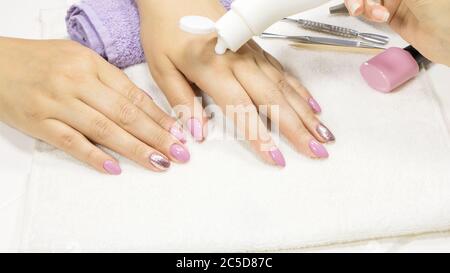 Il manicurista applica un idratante alla mano del cliente. MANICURE, procedura, idratazione. Lozione per le mani, crema. Cura della pelle. Salone di bellezza. Manicur Foto Stock