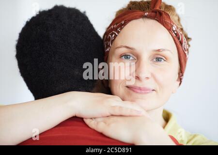 Ritratto di giovane donna che guarda la macchina fotografica mentre abbracciano l'uomo Foto Stock