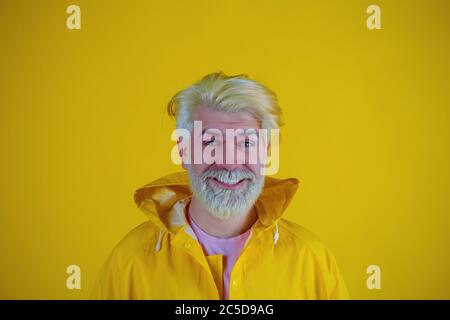 Uomo biondo con il portamonete che indossa un impermeabile in piedi su uno sfondo giallo isolato molto felice e sorridente Foto Stock