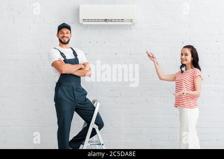 Un uomo che sorride guardando la telecamera vicino alla donna, che punta con la mano e tiene il telecomando Foto Stock