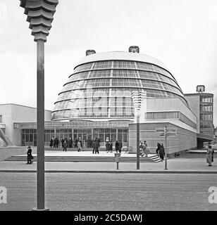 Una vista dell'Expo 1937 (Fiera Mondiale o esposizione) che si tiene a Parigi, Francia - qui la gente di fronte al Palais de l'Air (Palazzo dell'aria), un edificio moderno e suggestivo nella parte 'Sezioni Trasporti' del sito. Questo padiglione era una grande serie di gallerie progettate da Audoul, Hartwig e Gérodias. Ospitando mostre di aviazione, il pezzo centrale del padiglione Air è stata la vasta galleria curva in acciaio e vetro che ha fatto eco a un appendiabiti per aerei. All'interno erano giganteschi anelli di alluminio, che ricordano gli anelli di Saturno, circondavano un aereo in una mostra progettata da Robert e Sonia Delaunay. Foto Stock