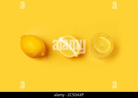 Disintossicare con limone su sfondo giallo. Limonata di agrumi. In estate, la frutta insisteva sull'acqua. Vista dall'alto con spazio per la copia. Disposizione piatta. Foto Stock