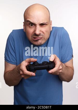 Arrabbiato uomo calvo gioca gioco al computer isolato su sfondo grigio studio Foto Stock