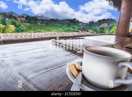 Caffè latte in una tazza bianca sul tavolo del ristorante con vista sulle montagne a distanza a Bali Foto Stock